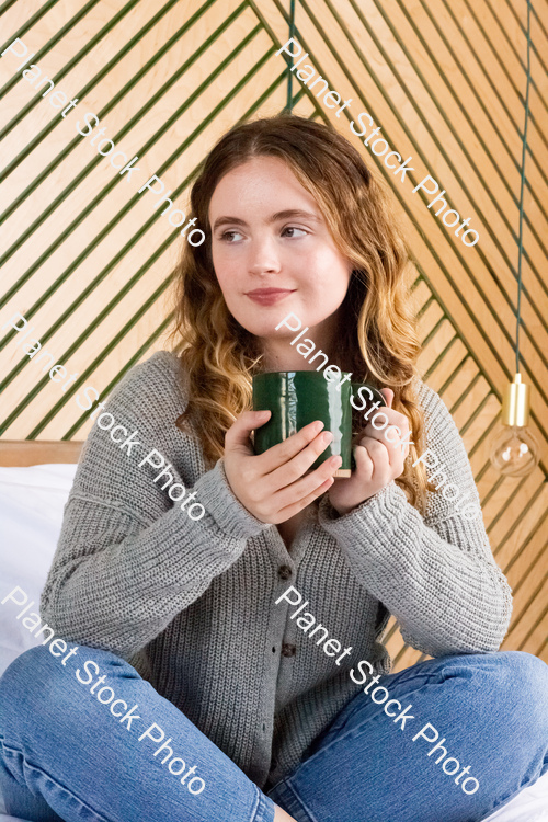 A girl sitting on the bed and enjoying a hot drink stock photo with image ID: 6c767ff0-ea07-4a0f-8c7e-205f53321721