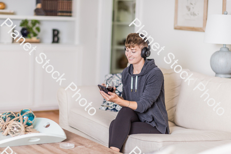A young lady sitting on the couch stock photo with image ID: a8fddbb4-13cf-46be-b730-4c7fadca2457