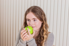 A girl sitting with an apple in her hand