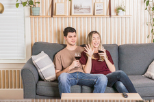 A young couple sitting on the couch and enjoying red wine